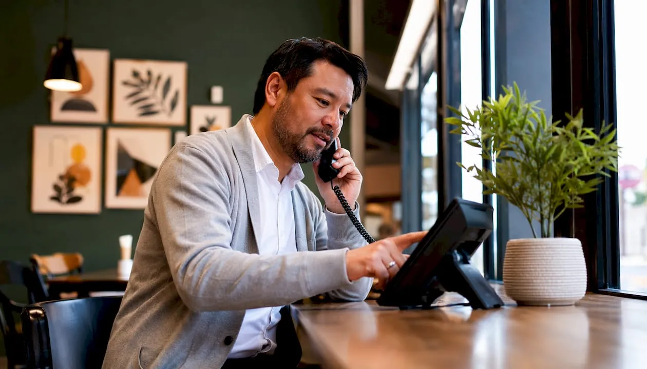 Hands dialing VoIP phone in home office