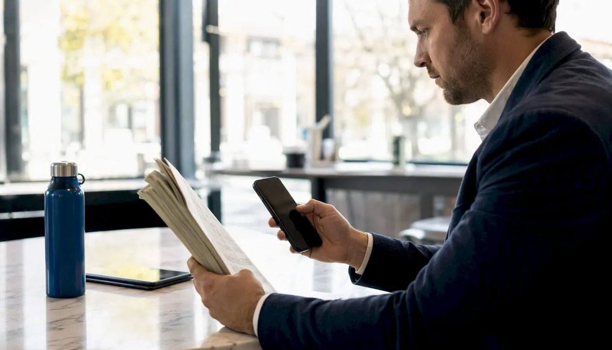 Person examining phone number with directory and smartphone