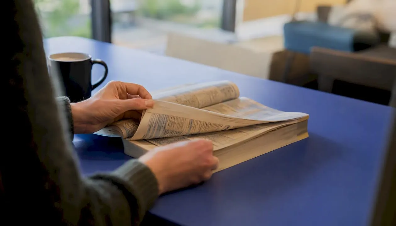 Hands flipping phone directory pages on desk