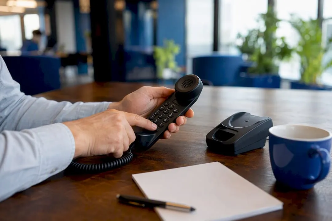 Hands dialing buttons on UK landline telephone