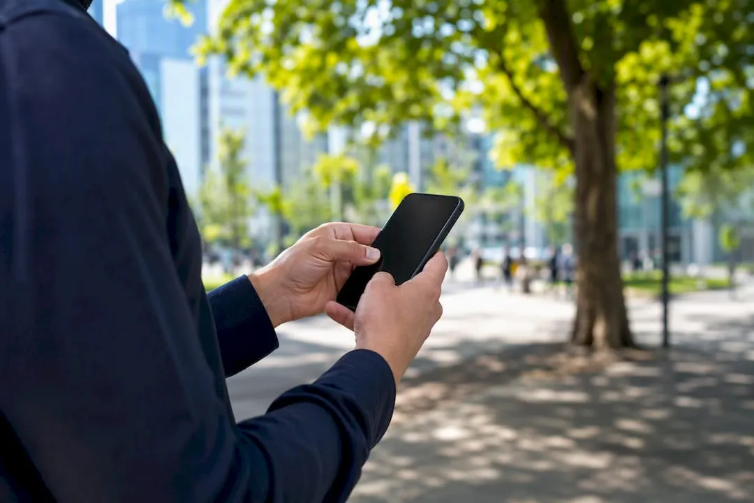 Hands holding smartphone near work van